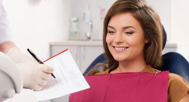 Patientin auf Zahnarztstuhl macht Angaben für Formular