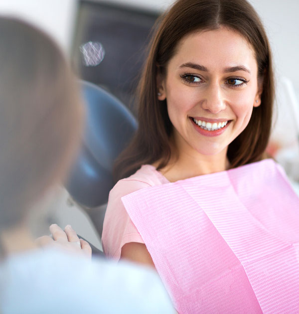 Patientin auf Zahnarztstuhl mit pinker Dentalserviette